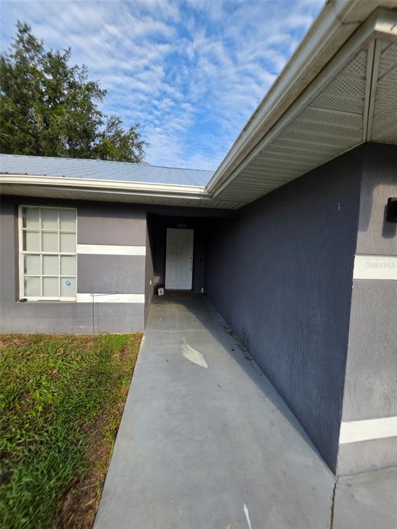 A gray house exterior features a white front door, a concrete walkway, and a metal roof — 720 SE PINE AVENUE, FORT MEADE, FL