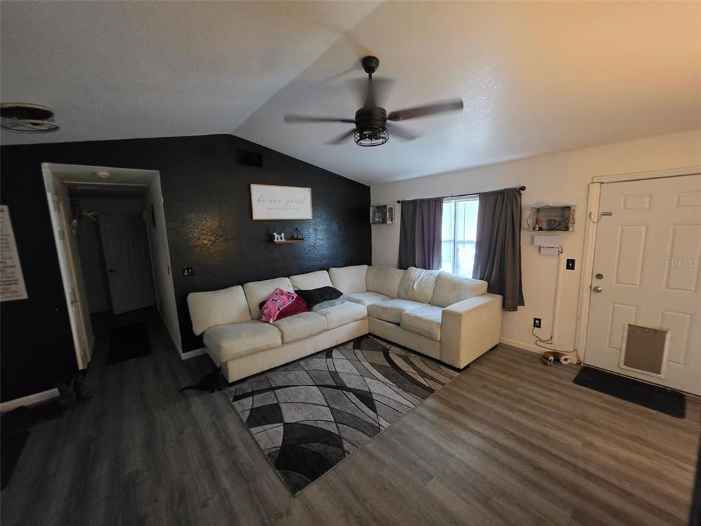A living room features a white sectional sofa, a geometric area rug, and a black accent wall — 720 SE PINE AVENUE, FORT MEADE, FL