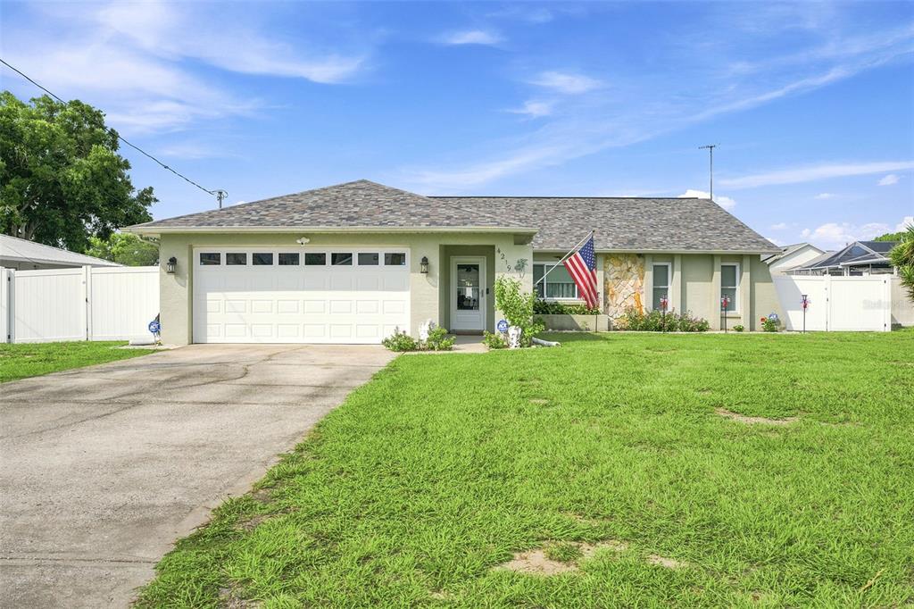 A single-story house with a white garage, stone facade, and an American flag — 4219 AUGUSTINE ROAD, SPRING HILL, FL