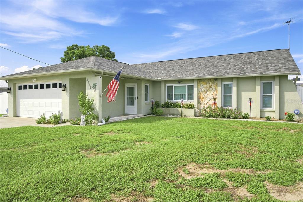 A single-story house with a light green exterior, a two-car garage, and a stone accent wall — 4219 AUGUSTINE ROAD, SPRING HILL, FL