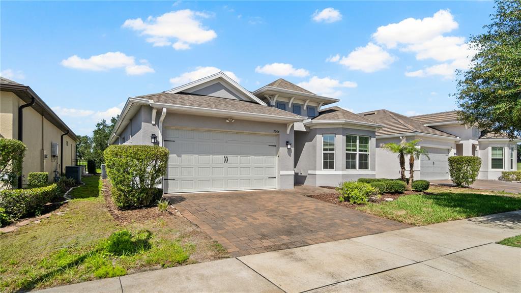 A single-story suburban house with a gray stucco exterior, a two-car garage, and a driveway — 7964 HANSON BAY PLACE, KISSIMMEE, FL