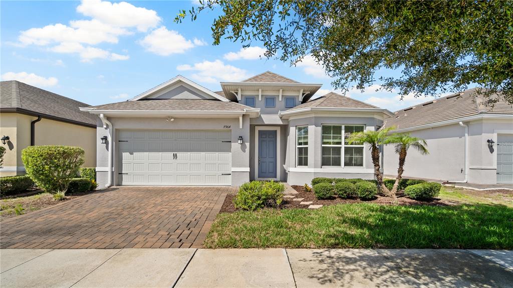 A single-story suburban house with a gray exterior, a two-car garage, and a paved driveway — 7964 HANSON BAY PLACE, KISSIMMEE, FL