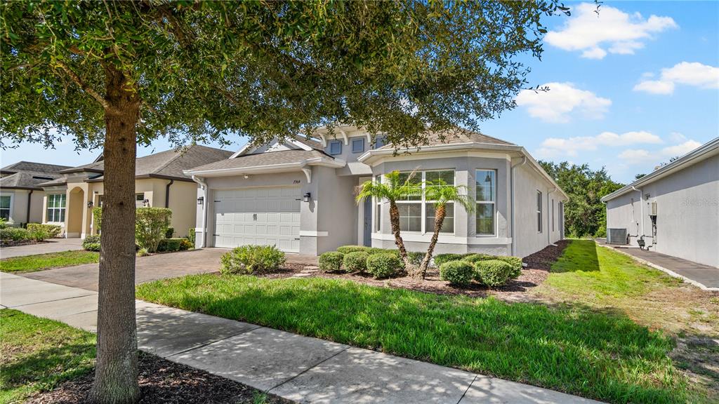 A single-story suburban house with a gray exterior, two-car garage, and a small palm tree — 7964 HANSON BAY PLACE, KISSIMMEE, FL