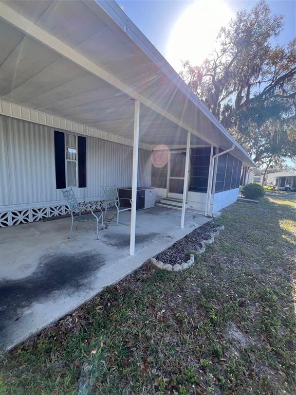 A covered concrete patio sits beside a mobile home with metal siding and lattice skirting — 11 SHADY LANE, PALMETTO, FL