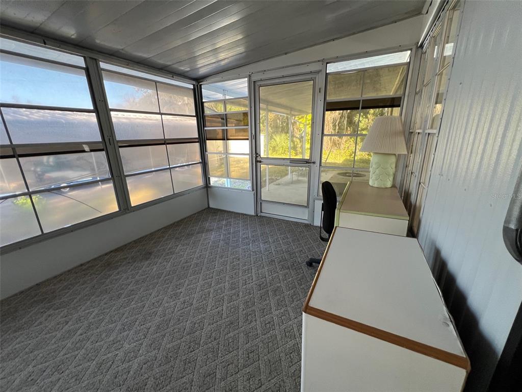 A sunroom features gray patterned carpeting, large windows, and a desk with a lamp — 11 SHADY LANE, PALMETTO, FL
