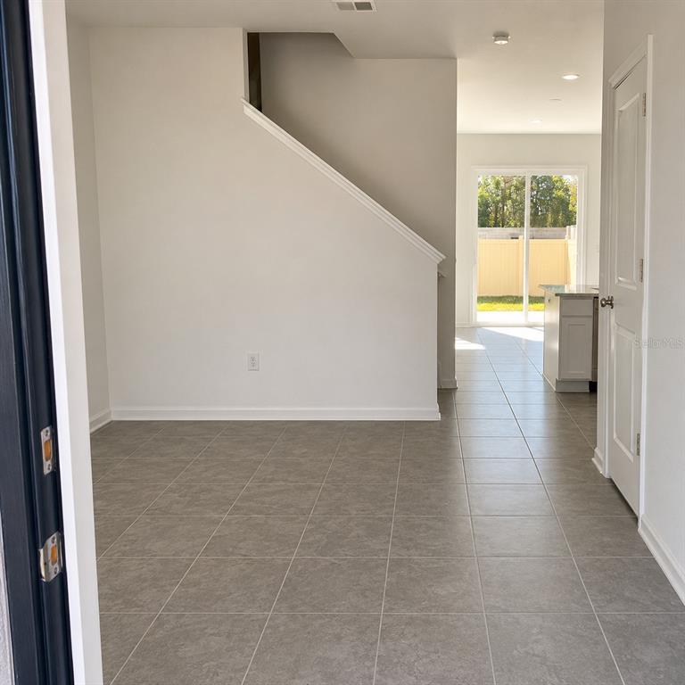 A view from a doorway showing a tiled floor, a staircase, and a rear sliding door — 2528 SKYLINE LOOP, KISSIMMEE, FL