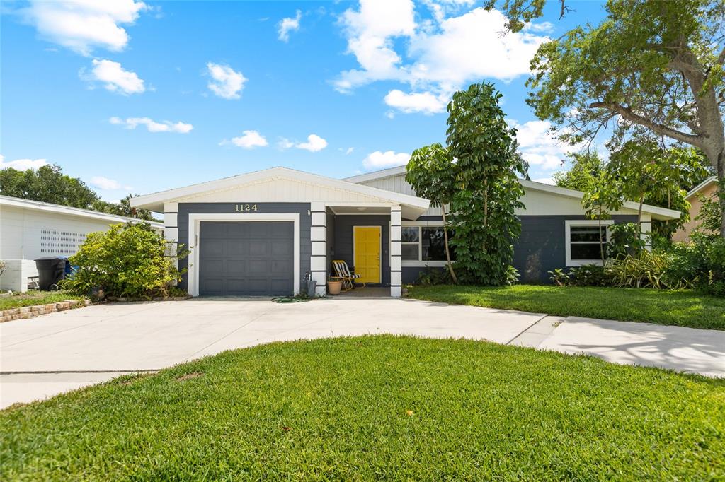 A single-story house with a gray exterior, yellow front door, and a concrete driveway — 1124 40TH AVENUE NE, ST PETERSBURG, FL