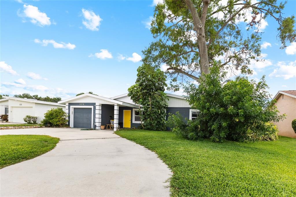 A single-story house with a yellow front door, gray siding, and a concrete driveway — 1124 40TH AVENUE NE, ST PETERSBURG, FL