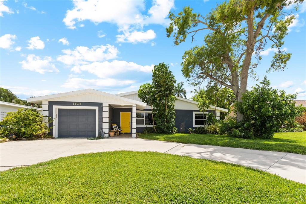 A single-story house with a gray exterior, yellow front door, and a paved driveway — 1124 40TH AVENUE NE, ST PETERSBURG, FL