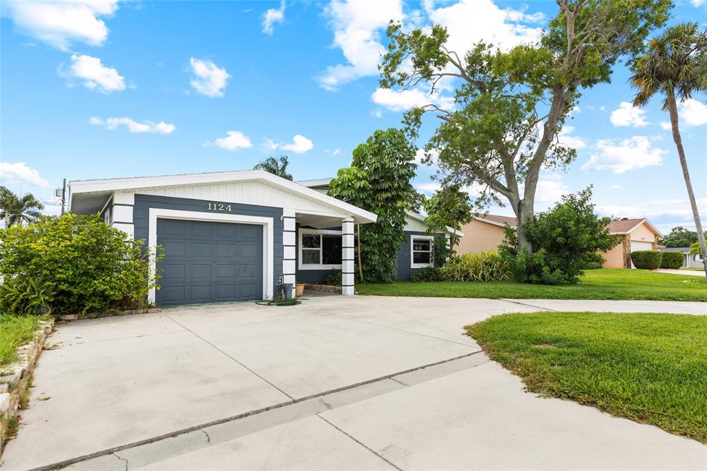 A single-story house with a gray garage, white trim, and a concrete driveway — 1124 40TH AVENUE NE, ST PETERSBURG, FL
