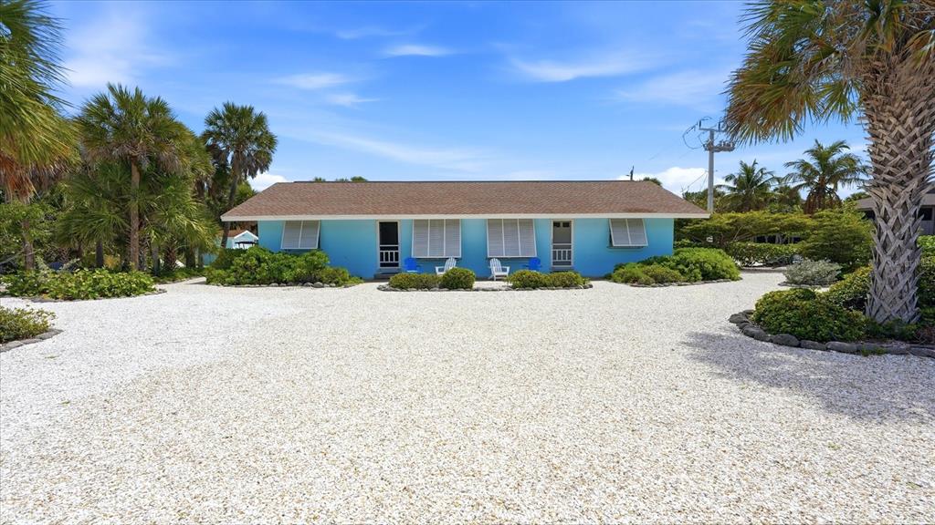 A single-story blue house with a brown roof sits behind a large gravel driveway — 201 WHEELER ROAD, BOCA GRANDE, FL
