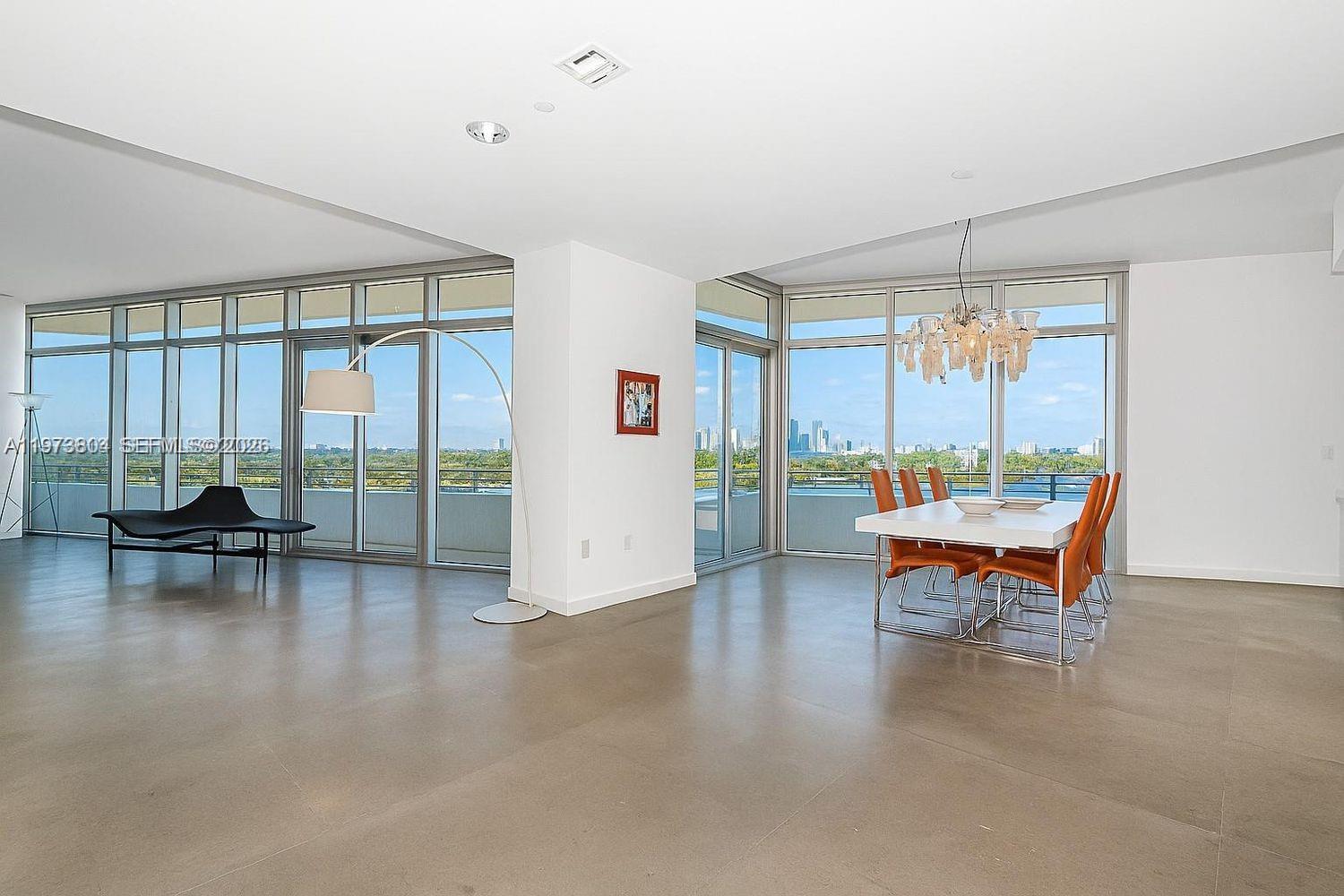 A bright, open-concept living and dining area features floor-to-ceiling windows and polished concrete floors — 6101 Aqua Ave # 702, Miami Beach FL 33141, MIAMI BEACH, FL