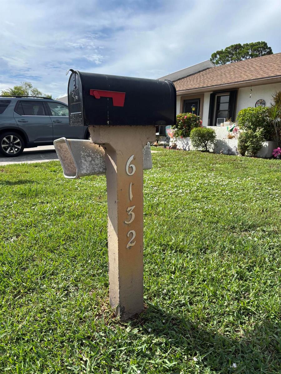 A black mailbox sits atop a concrete post displaying the house number 6132 — 6132 Fairfield Circle # 7, FL 33463, FL