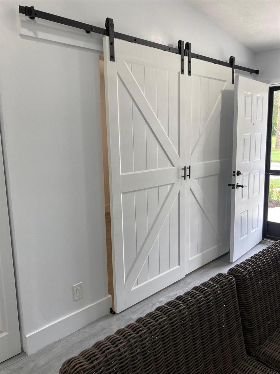 A room features white double barn doors with black hardware and a wicker sofa — 6132 Fairfield Circle # 7, FL 33463, FL