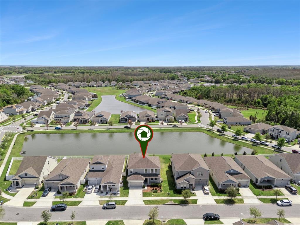 An aerial view shows a two-story suburban house situated along a pond — 4360 SEVEN CANYONS DRIVE, KISSIMMEE, FL