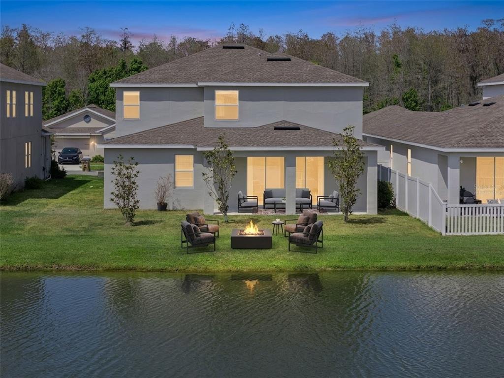 A two-story house with a backyard fire pit area overlooking a pond — 4360 SEVEN CANYONS DRIVE, KISSIMMEE, FL
