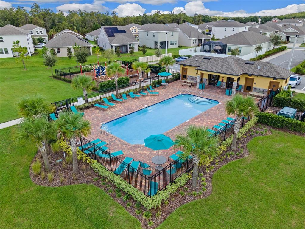 An aerial view of a community swimming pool with lounge chairs and a clubhouse — 4360 SEVEN CANYONS DRIVE, KISSIMMEE, FL