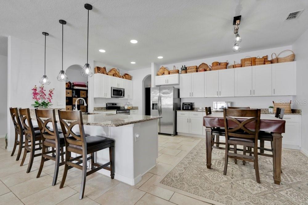 A kitchen with white cabinets, granite countertops, a center island, and a dining area — 1086 ROCK CREEK STREET, APOPKA, FL