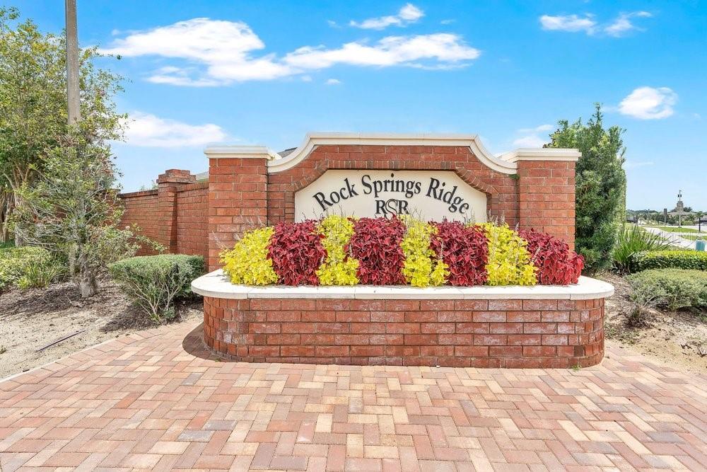 A brick monument sign for Rock Springs Ridge features colorful plants and a stone ledge — 1086 ROCK CREEK STREET, APOPKA, FL