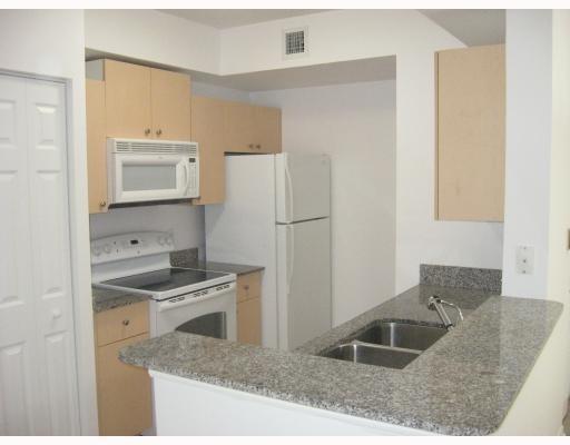 A kitchen features light wood cabinets, granite countertops, a white stove, and a white refrigerator — 2421 Centergate Drive # 104, Miramar FL 33025, MIRAMAR, FL