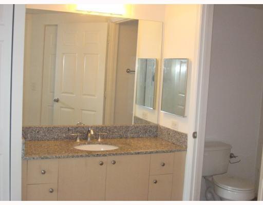 A bathroom vanity with a granite countertop and mirror next to a toilet — 2421 Centergate Drive # 104, Miramar FL 33025, MIRAMAR, FL