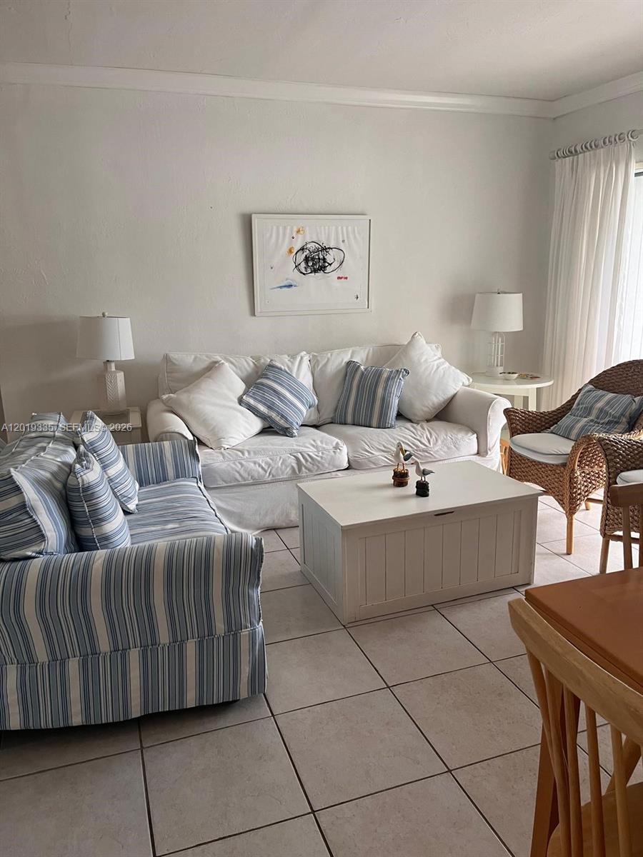 A living room features a white sofa, a blue-striped loveseat, and a wicker chair — 290 Sunrise Dr # 208, Key Biscayne FL 33149, KEY BISCAYNE, FL