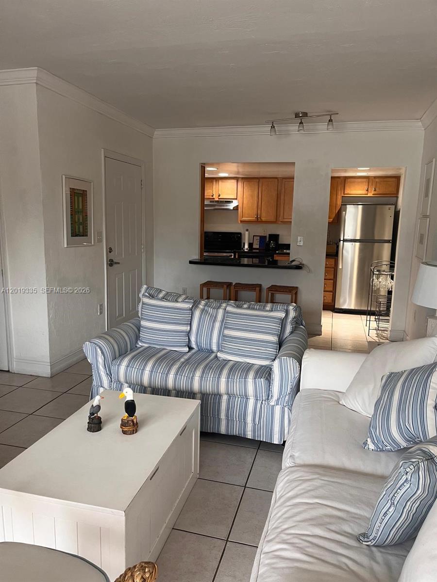 A living room with a striped sofa, white coffee table, and an open kitchen pass-through — 290 Sunrise Dr # 208, Key Biscayne FL 33149, KEY BISCAYNE, FL