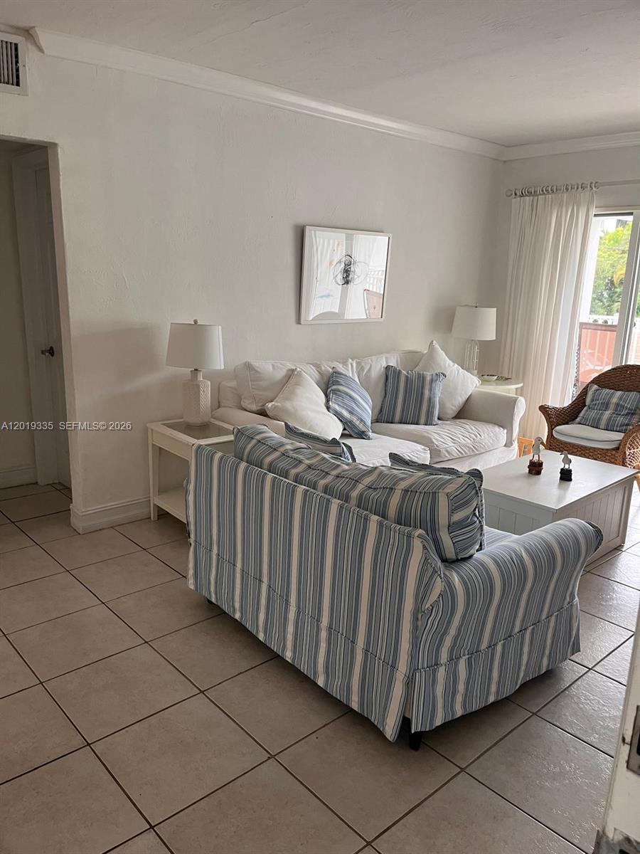 A living room features a striped sofa, a white sofa, and tile flooring — 290 Sunrise Dr # 208, Key Biscayne FL 33149, KEY BISCAYNE, FL