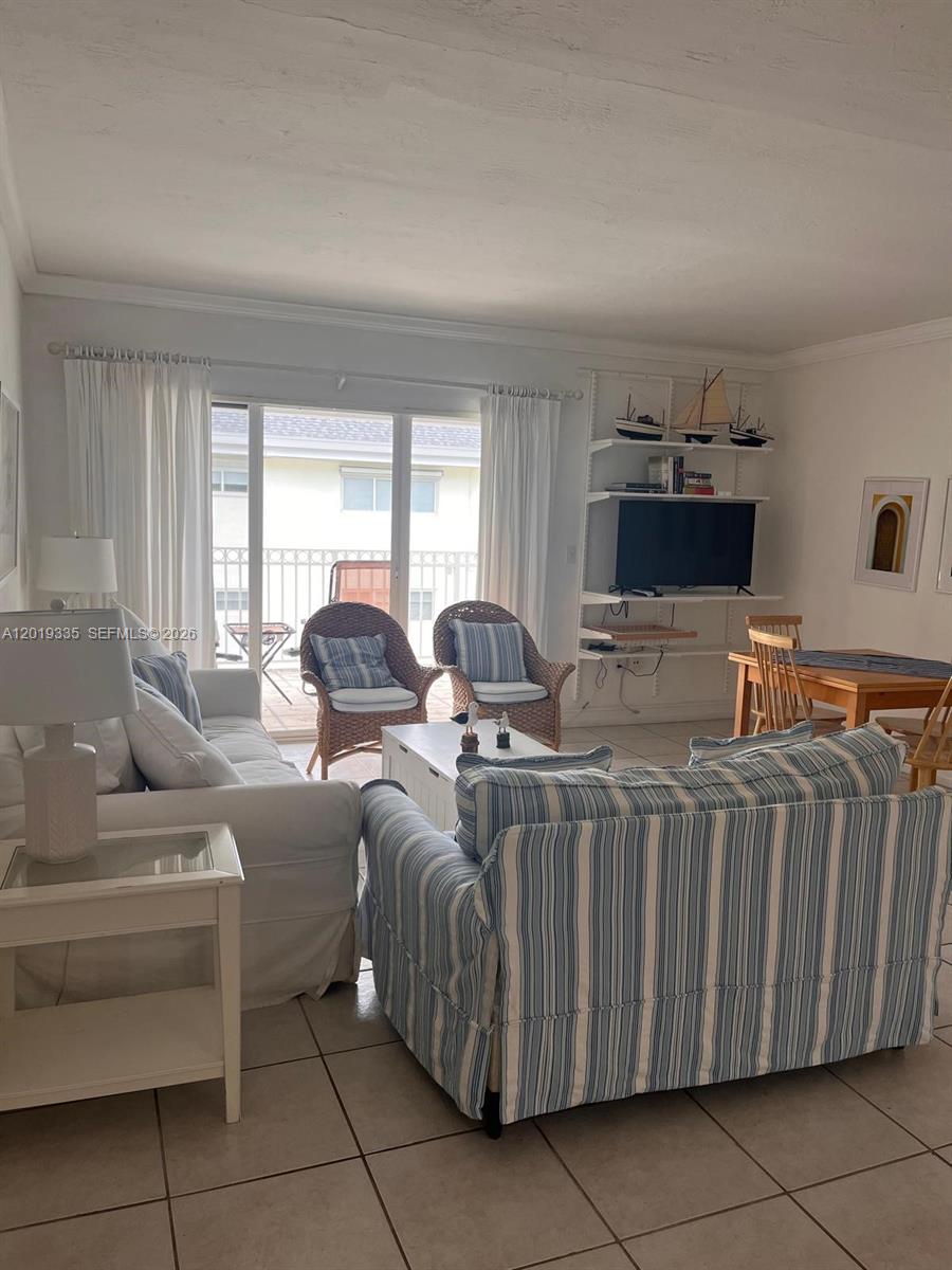 A living room features a striped sofa, wicker chairs, a television, and a balcony view — 290 Sunrise Dr # 208, Key Biscayne FL 33149, KEY BISCAYNE, FL