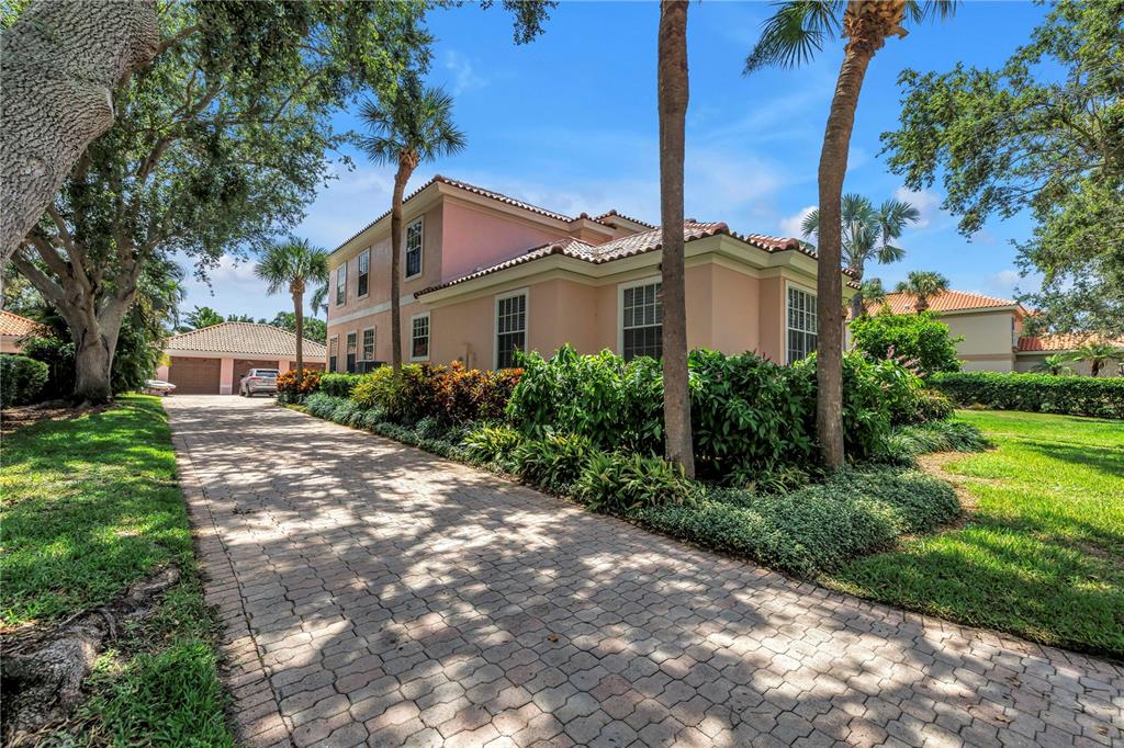 A two-story peach-colored house features a paved driveway, palm trees, and a detached garage — 4930 SANDPIPER LANE S, ST PETERSBURG, FL