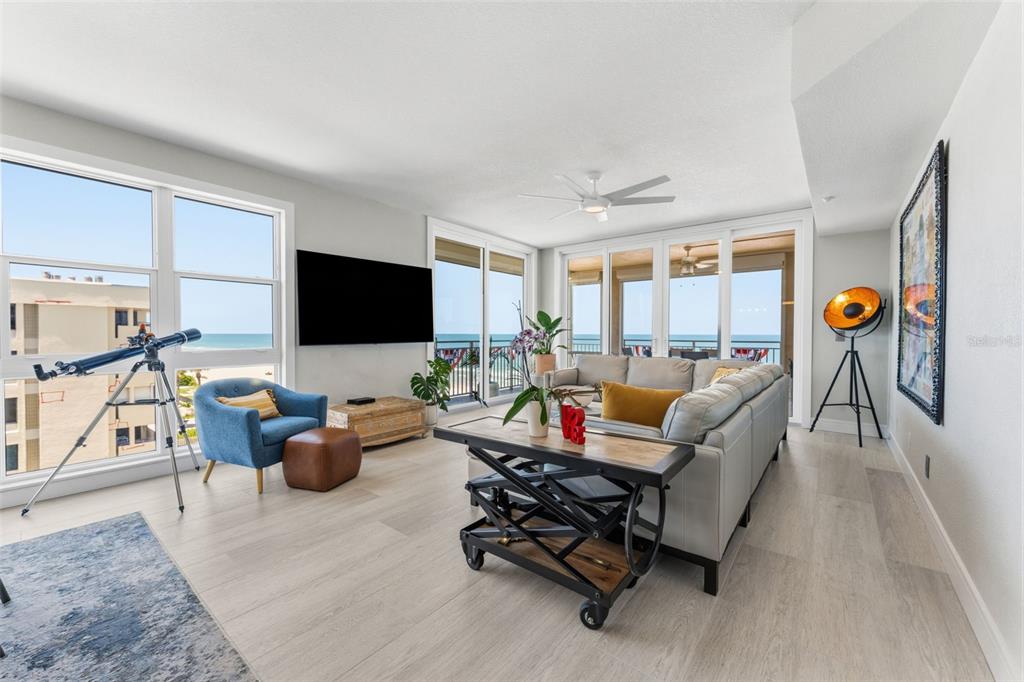 A bright living room features light wood floors, a sectional sofa, and ocean views — 2 15TH AVENUE UNIT 401, INDIAN ROCKS BEACH, FL