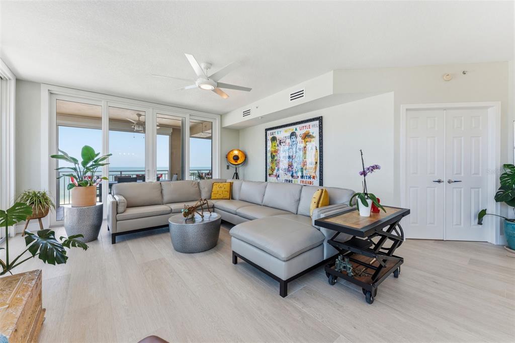 A living room features a light gray sectional sofa, a metal coffee table, and ocean views — 2 15TH AVENUE UNIT 401, INDIAN ROCKS BEACH, FL