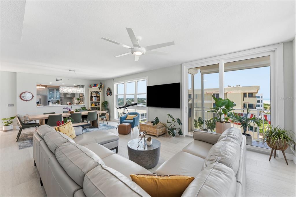 A living room with a sectional sofa, dining area, and large windows overlooking a balcony — 2 15TH AVENUE UNIT 401, INDIAN ROCKS BEACH, FL