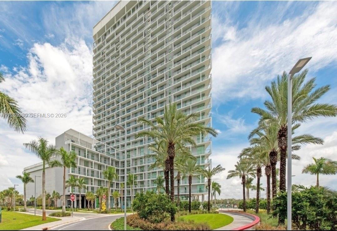A tall modern residential high-rise building stands surrounded by palm trees and landscaping — 2000 Metropica Way # 2507, Sunrise FL 33323, SUNRISE, FL