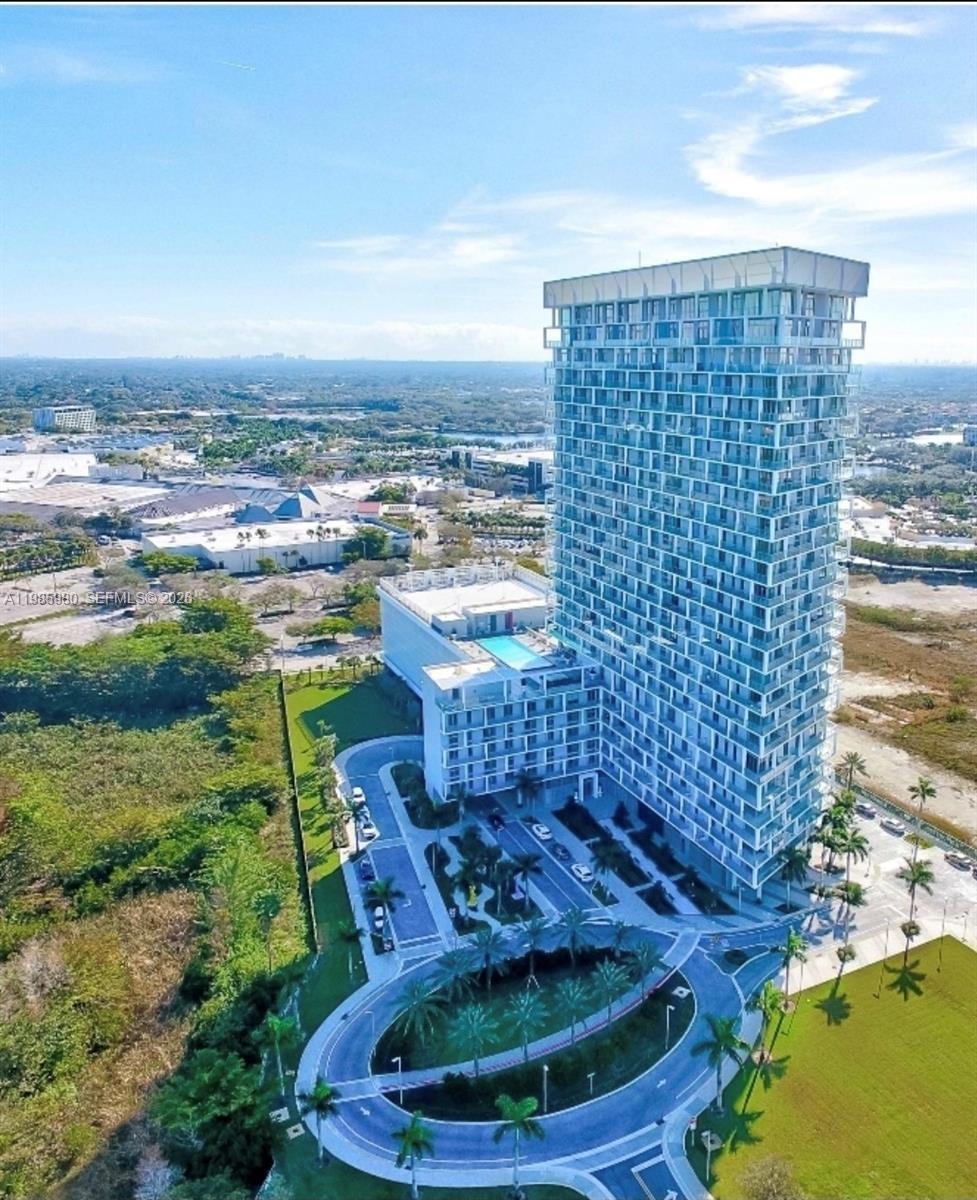 An aerial view shows a tall glass residential tower with a pool deck and driveway — 2000 Metropica Way # 2507, Sunrise FL 33323, SUNRISE, FL