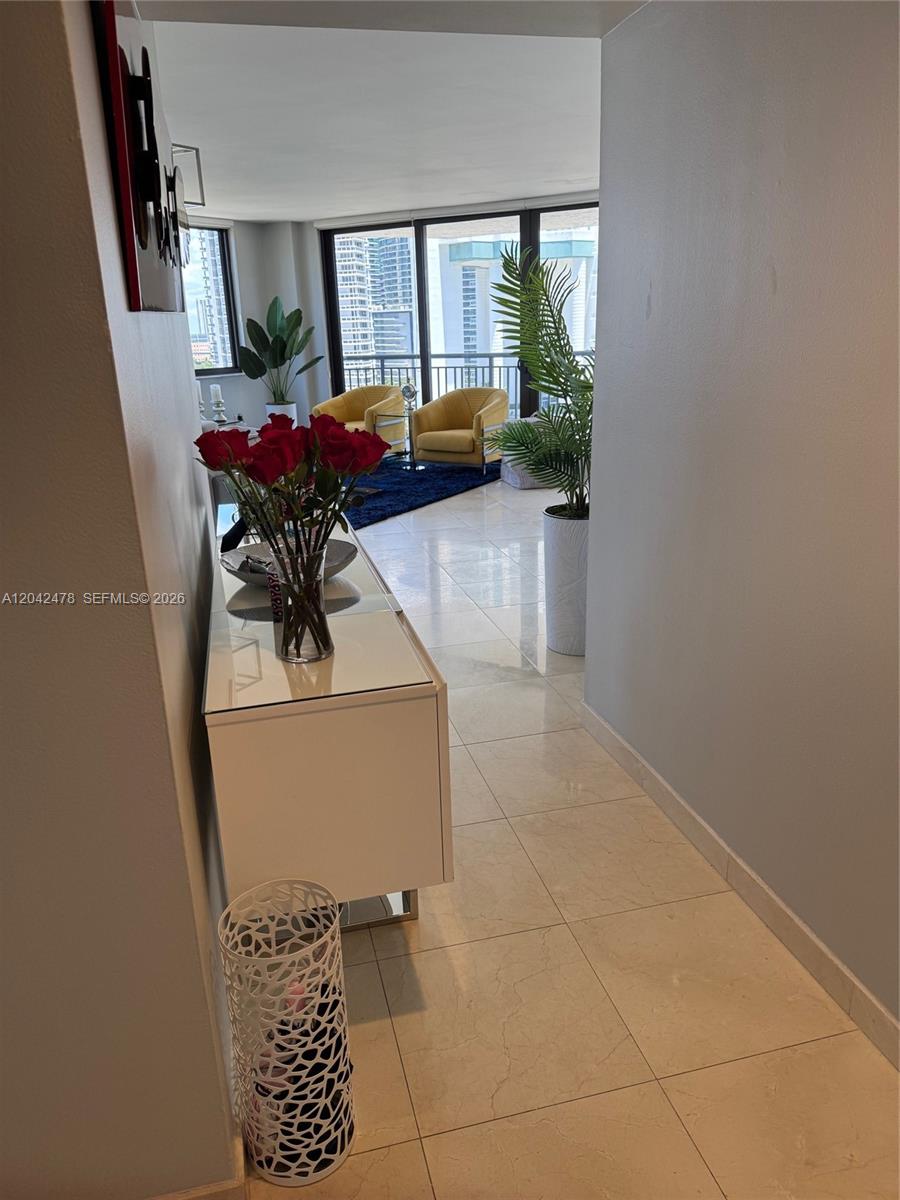 A hallway with a white console table and flowers leads into a bright living area — 540 Brickell Key Dr # 1513, Miami FL 33131, MIAMI, FL