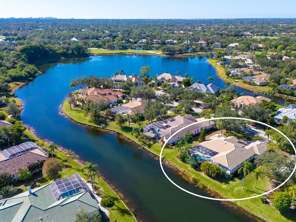 An aerial view shows a waterfront house with a screened pool and tile roof — 7311 WESTMINSTER COURT, UNIVERSITY PARK, FL