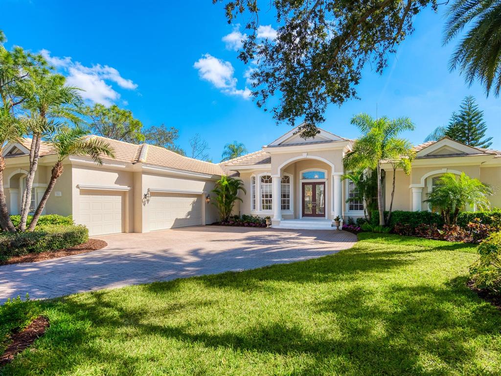 A single-story house with a beige exterior, a paved driveway, and a manicured front lawn — 7311 WESTMINSTER COURT, UNIVERSITY PARK, FL
