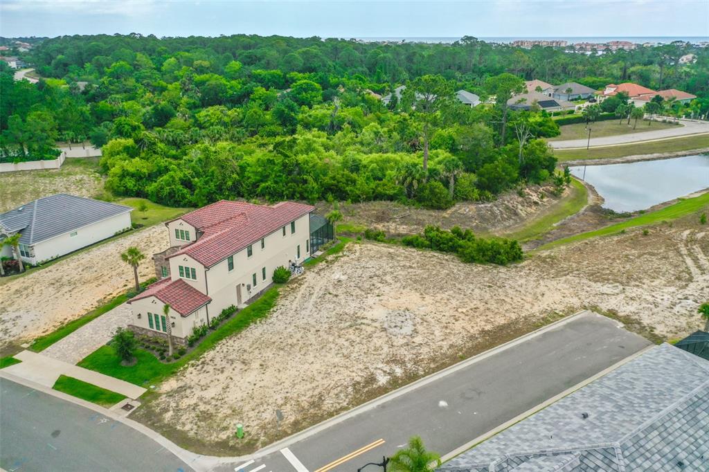 An aerial view shows a two-story house next to a vacant lot and a pond — 14 RIO VISTA DRIVE, PALM COAST, FL