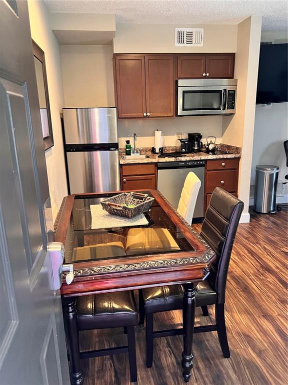 A small kitchen features stainless steel appliances, wood cabinets, and a dining table with chairs — 3100 PARKWAY BOULEVARD UNIT 417, KISSIMMEE, FL