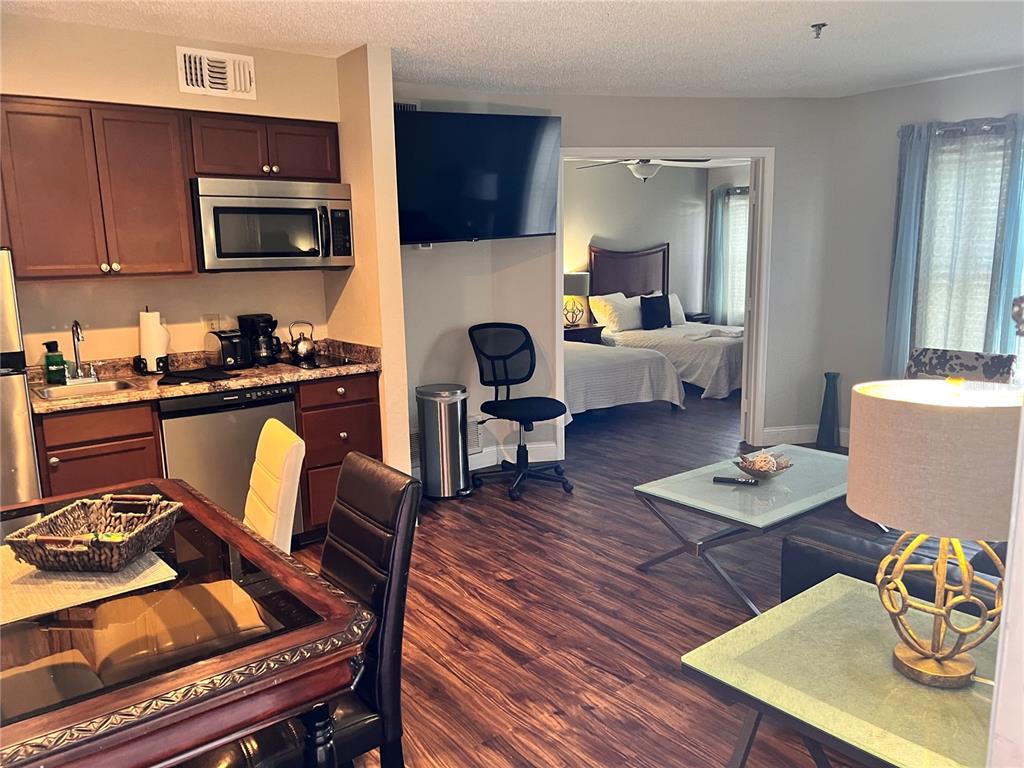 An open-concept kitchen, dining area, and living room lead into a bedroom with two beds — 3100 PARKWAY BOULEVARD UNIT 417, KISSIMMEE, FL