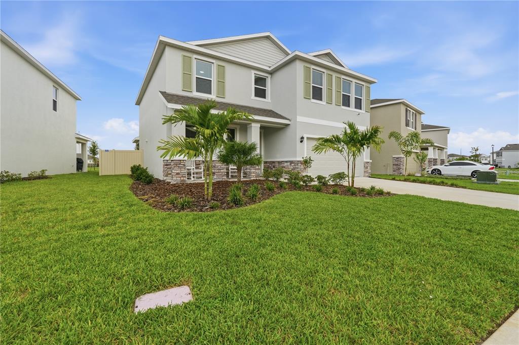 A two-story suburban house with light gray siding, stone accents, and a front lawn — 5117 ROSADO RUN, BRADENTON, FL
