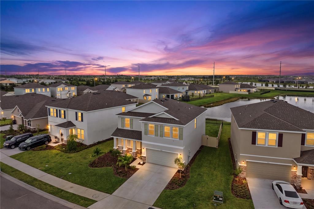 An aerial view shows suburban houses with driveways and lawns near a small retention pond — 5117 ROSADO RUN, BRADENTON, FL