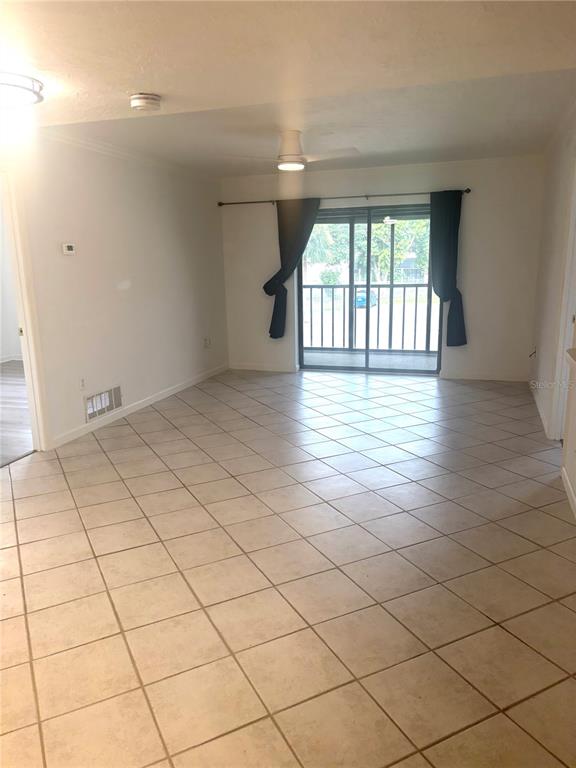 An empty room features light-colored tile flooring, a ceiling fan, and sliding glass balcony doors — 503 ALBEE FARM ROAD UNIT B28, VENICE, FL