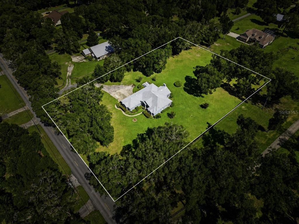 An aerial view shows a house with a gray roof situated on a large, grassy lot — 2111 SUN VALLEY LANE, DELAND, FL