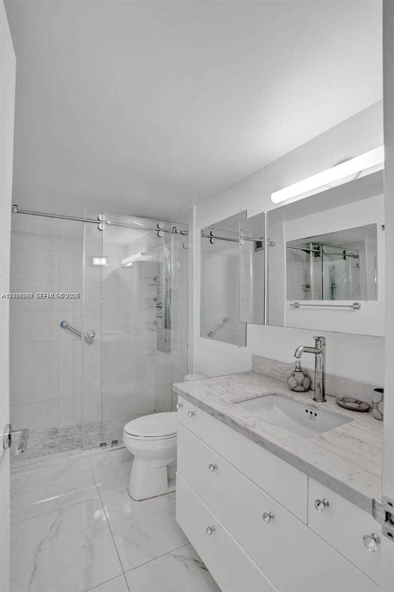 A modern bathroom features a white vanity, marble countertop, and a glass-enclosed walk-in shower — 2500 Parkview Dr # 1008, Hallandale Beach FL 33009, HALLANDALE BEACH, FL