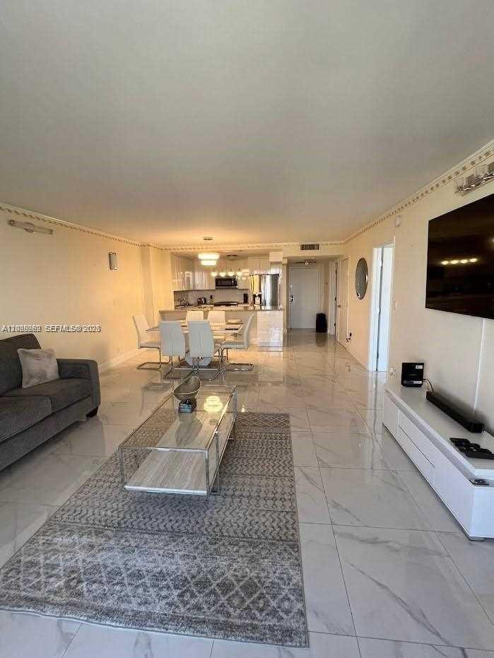An open-concept living and dining area features white tile floors and modern furniture — 2500 Parkview Dr # 1008, Hallandale Beach FL 33009, HALLANDALE BEACH, FL
