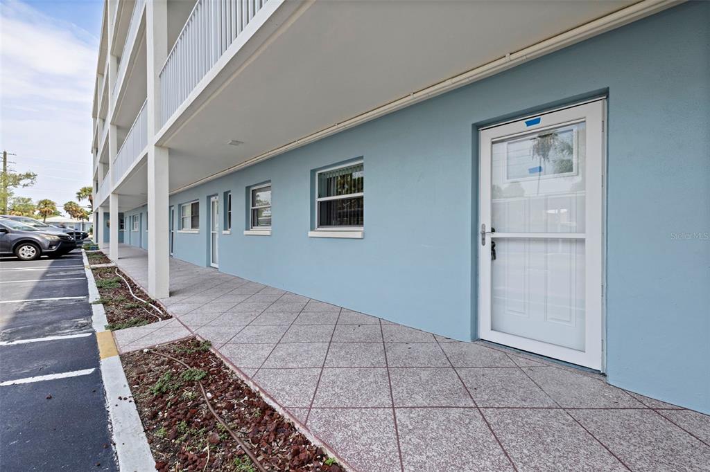A multi-story blue apartment building features exterior staircases, white railings, and a paved parking lot — 6363 GULF WINDS DRIVE UNIT 131, ST PETE BEACH, FL