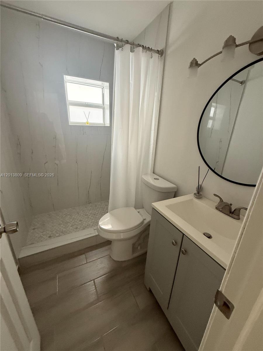 A bathroom features a walk-in shower, a toilet, and a vanity with a round mirror — 613 NW 15th Ave, Pompano Beach FL 33069, POMPANO BEACH, FL