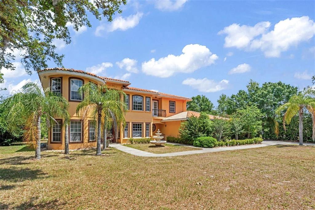 A two-story, orange-stucco house with a tile roof, a front fountain, and palm trees — 13161 LAKE BUTLER BOULEVARD, WINDERMERE, FL